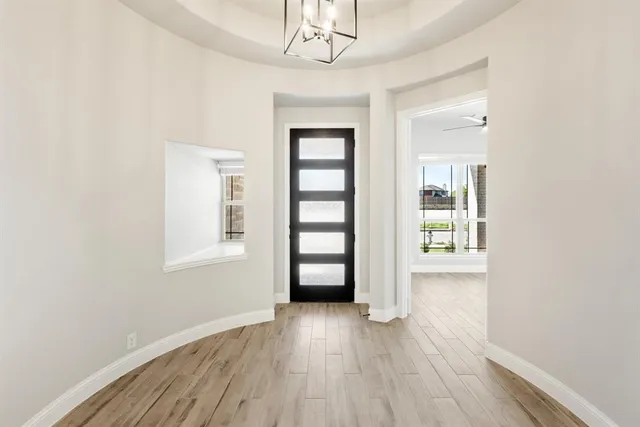 an empty room with wooden floor closet and windows