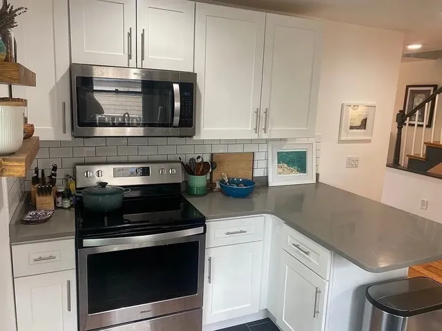 a kitchen with stainless steel appliances granite countertop white cabinets and stove