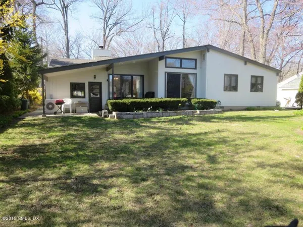 a view of a house with a yard and chairs