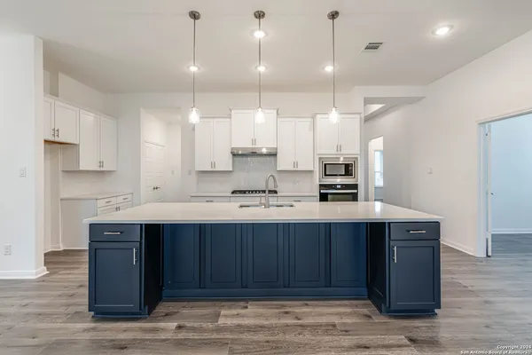 a kitchen with a sink a stove a refrigerator and white cabinets