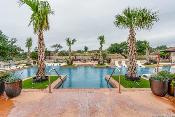 an aerial view of a swimming pool with a yard and outdoor seating