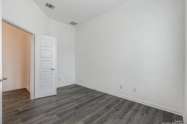 an empty room with wooden floor & windows