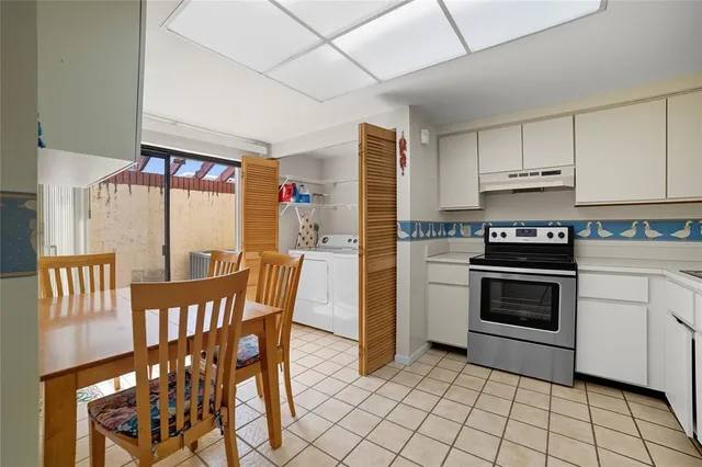 a kitchen with stainless steel appliances a stove a sink cabinets and a dining table
