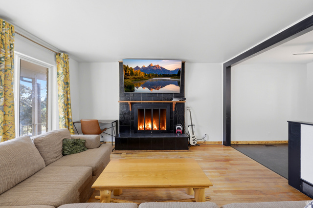 1486 3rd Street Ogden, UT 84404 - Photo 3 of 26 Living area featuring a black tile fireplace with a wood mantle, wood-finish flooring, white walls, and a large window