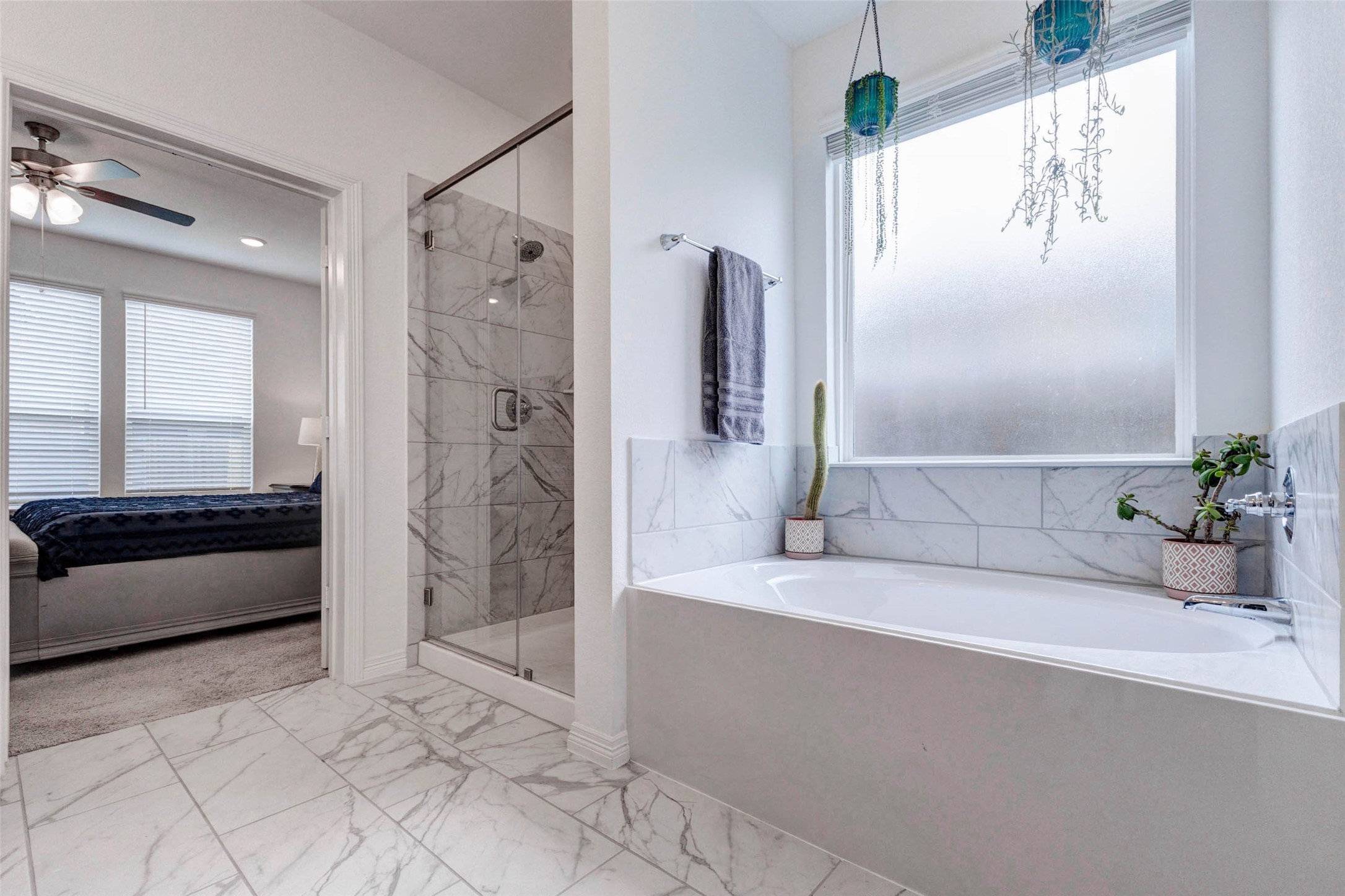 32418 Fly Fish Way Fulshear, TX 77441 - Photo 20 of 40 The deep soaking tub is beautifully positioned beneath a rain glass window that fills the space with soft, natural light while maintaining complete privacy. The marbled tile surround ties seamlessly into the walk-in shower just steps away, creating a cohesive and luxurious feel throughout the entire ensuite.