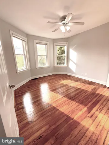 a view of empty room with wooden floor and fan