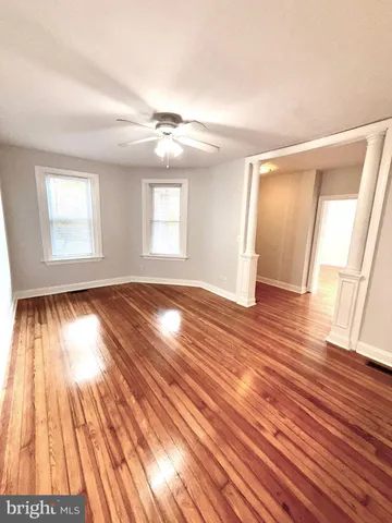 a view of empty room with wooden floor and fan