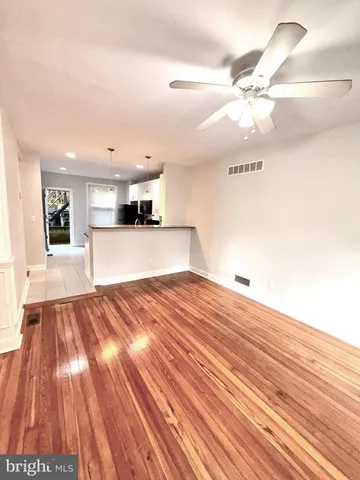a view of a room with wooden floor and a ceiling fan