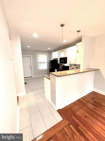 a kitchen with stainless steel appliances kitchen island granite countertop a refrigerator a stove and a sink with granite countertops