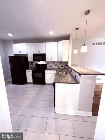 a view of a kitchen with kitchen island granite countertop a refrigerator a stove top oven and a sink