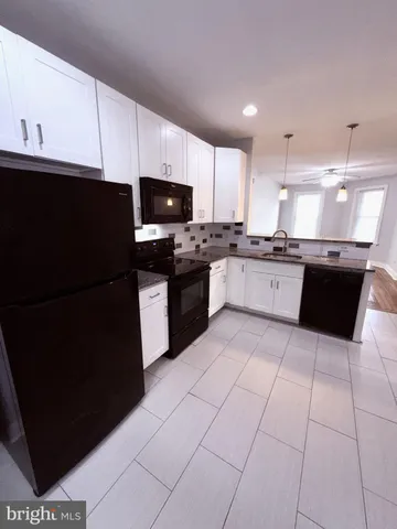 a large kitchen with granite countertop a stove a sink dishwasher and a refrigerator with wooden cabinets