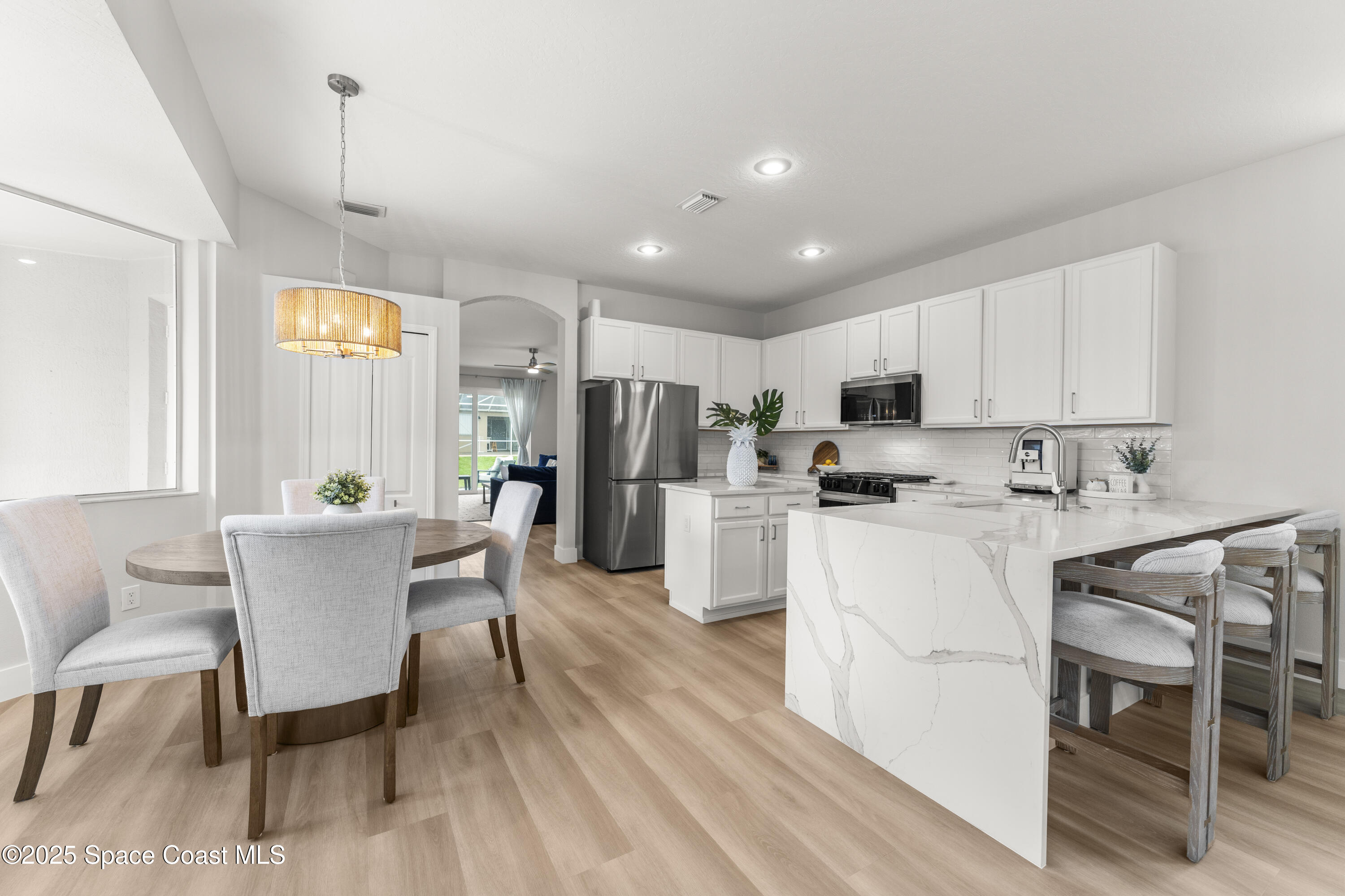 3053 Jacobaeus Lane Indialantic, FL 32903 - Photo 10 of 35 a dining room with stainless steel appliances kitchen island granite countertop a dining table chairs and a refrigerator