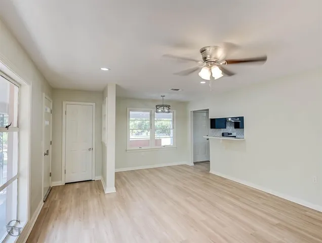 a view of empty room with wooden floor and fan