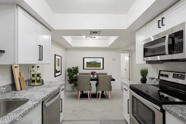 a kitchen with granite countertop stainless steel appliances a sink stove top oven and cabinets