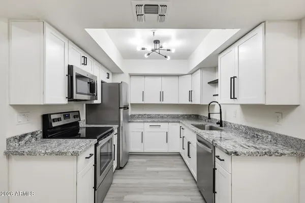 a kitchen with granite countertop a stove sink and microwave