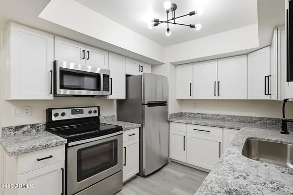 a kitchen with granite countertop white cabinets white appliances with a sink and dishwasher
