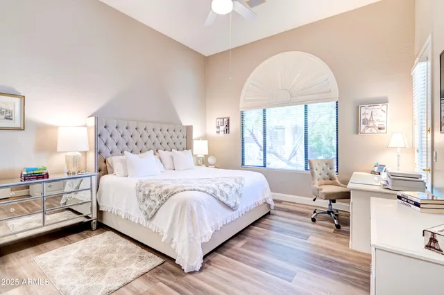 a bedroom with a bed a large window with table and chairs