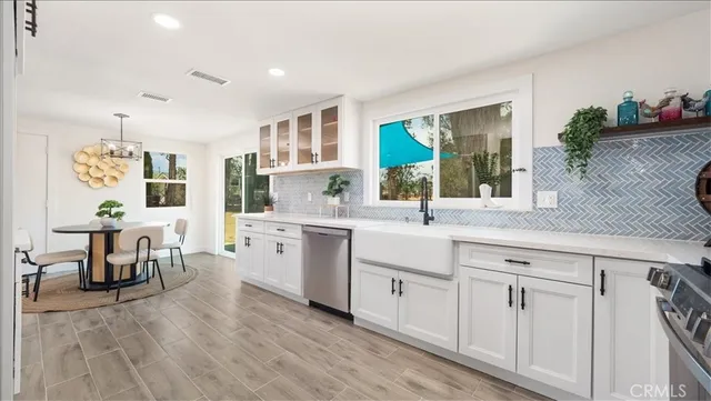 a large white kitchen with a lot of cabinets and wooden floor