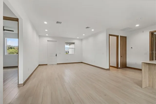 an empty room with wooden floor and windows