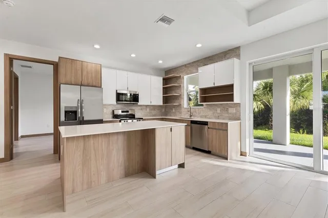 a large kitchen with stainless steel appliances granite countertop a stove a sink dishwasher a refrigerator and a oven with wooden floor