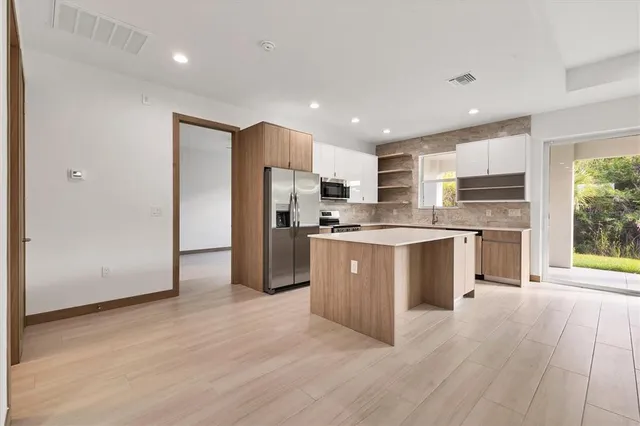 a kitchen with stainless steel appliances granite countertop a refrigerator a sink dishwasher a stove with large oven and wooden floors