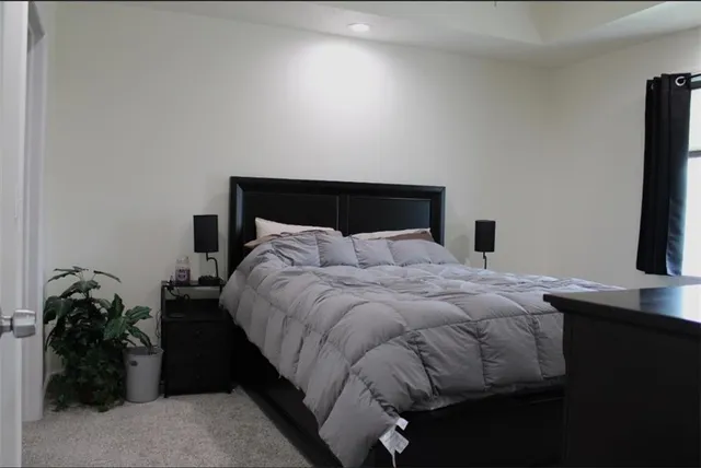 a bedroom with a bed and a flat tv screen on the dresser