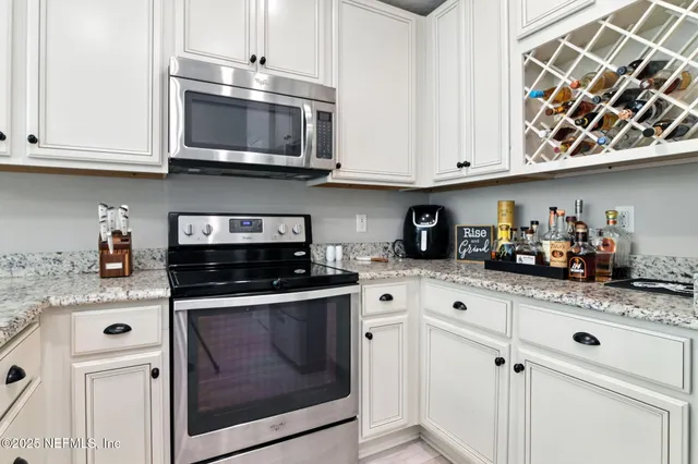 a kitchen with stainless steel appliances granite countertop white cabinets and a stove a oven with white countertops