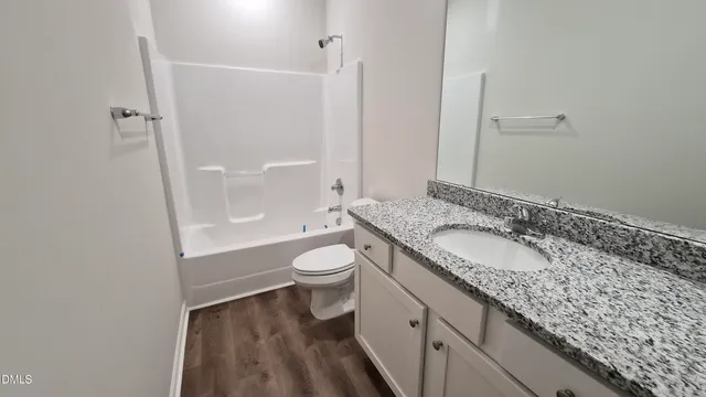 a bathroom with a granite countertop sink a toilet and shower