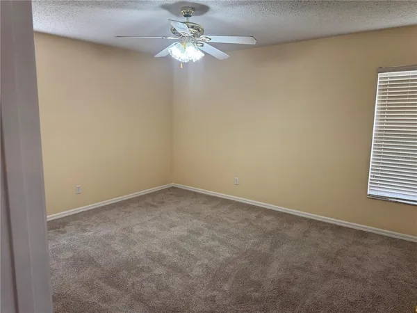an empty room with a chandelier fan and windows