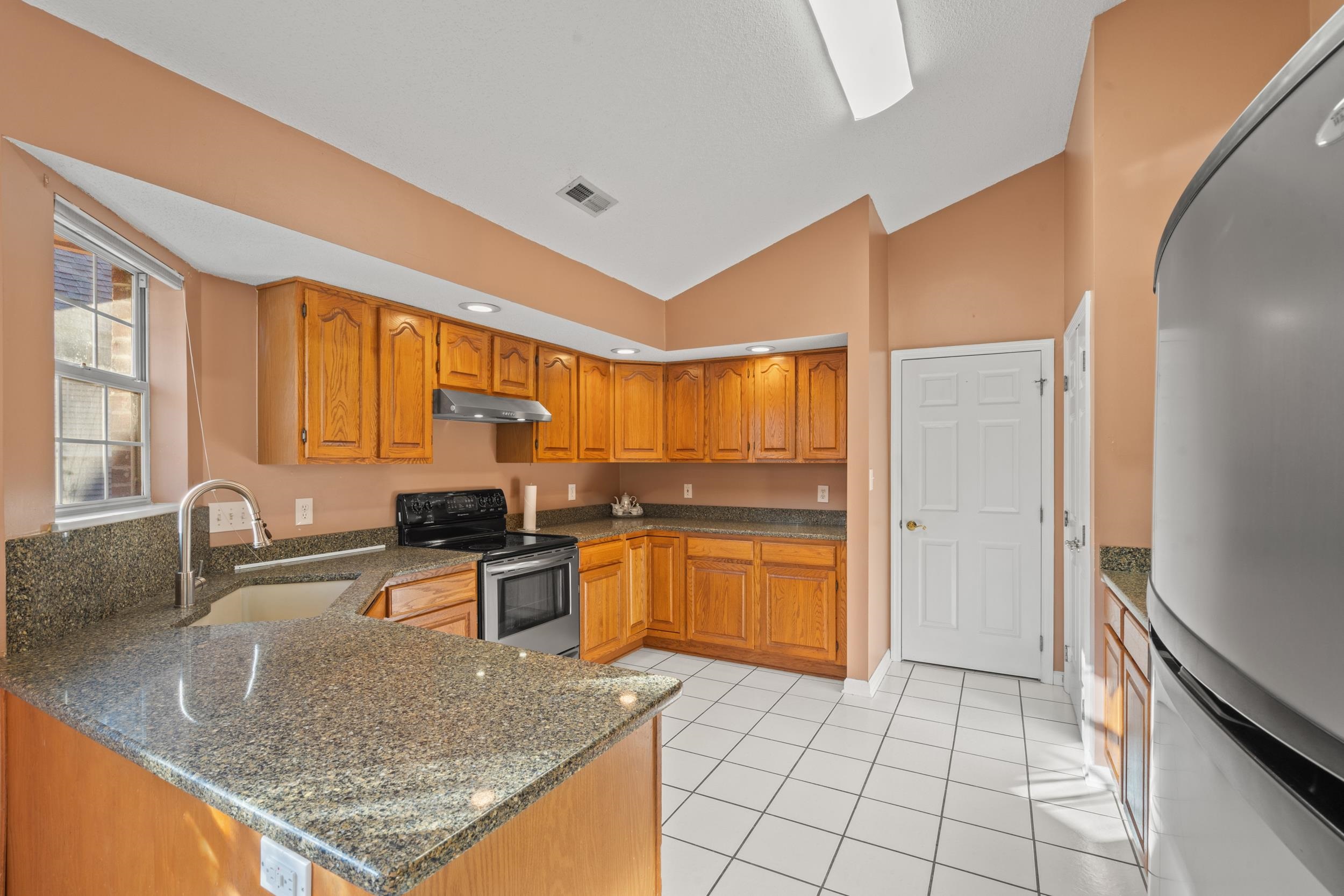 3106 Robyn Court Little River, SC 29566 - Photo 9 of 37 Kitchen featuring freestanding refrigerator, lofted ceiling, stainless steel electric stove, dark stone countertops, and brown cabinetry