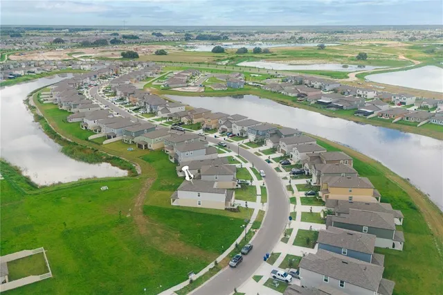 an aerial view of residential houses with outdoor space and trees