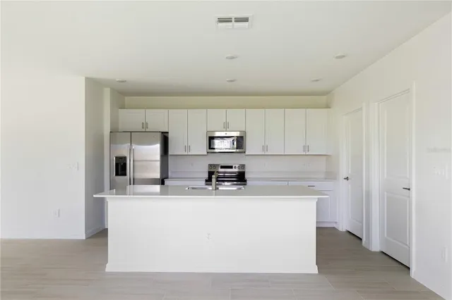 a kitchen with kitchen island a sink a stove a refrigerator and cabinets