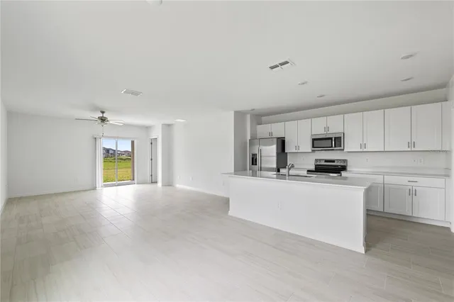 a kitchen with stainless steel appliances a sink a stove a refrigerator cabinets and a window