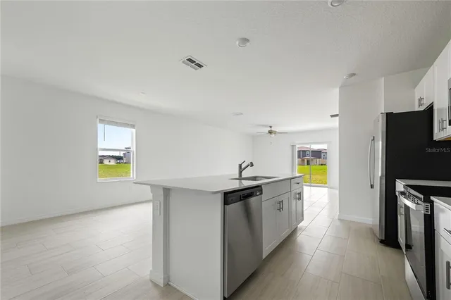 a kitchen with stainless steel appliances a sink a stove a refrigerator cabinets and a counter top space