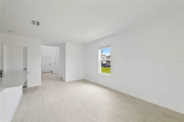 a view of an empty room with a window and wooden floor