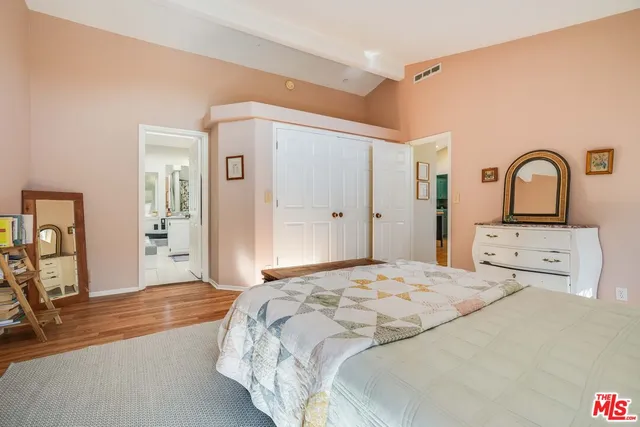 a bedroom with a bed and a large mirror on the dresser