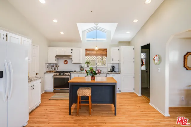 a dining room with stainless steel appliances granite countertop a refrigerator oven a sink dishwasher and a dining table with wooden floor