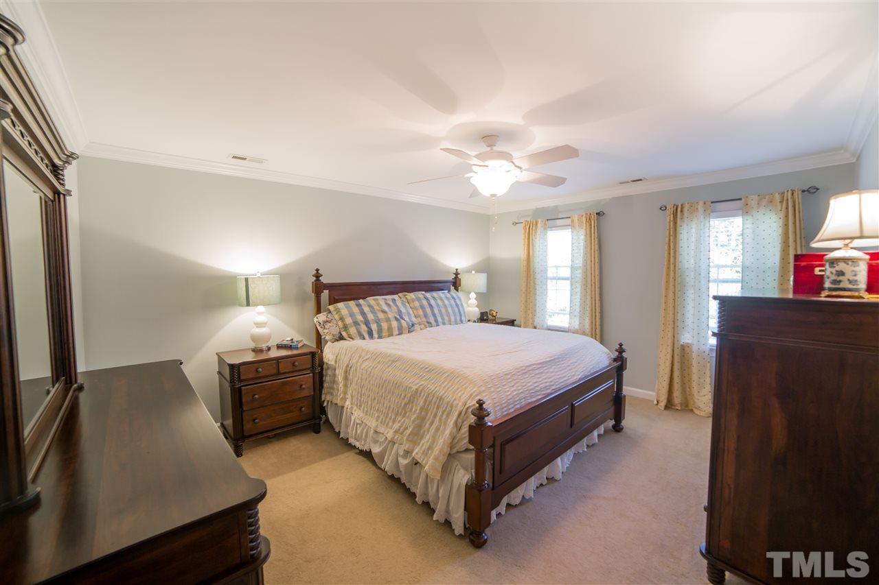 5228 Caber Road Raleigh, NC 27613 - Photo 14 of 25 a spacious bedroom with a bed and a chandelier