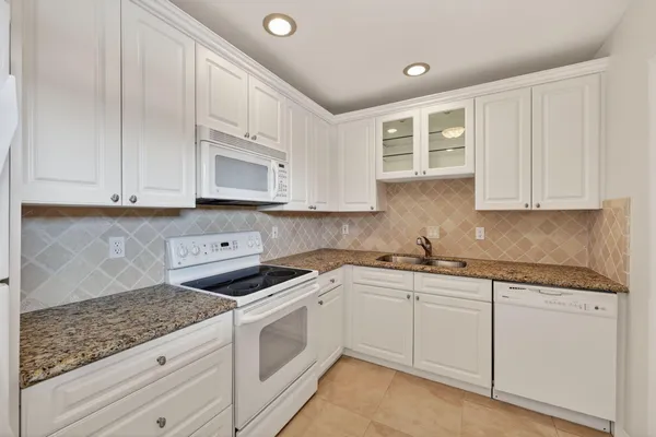a kitchen with white cabinets granite counter tops and a stove