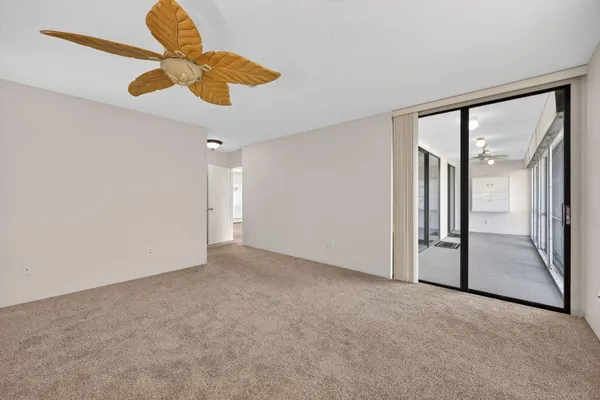 an empty room with a chandelier fan and windows