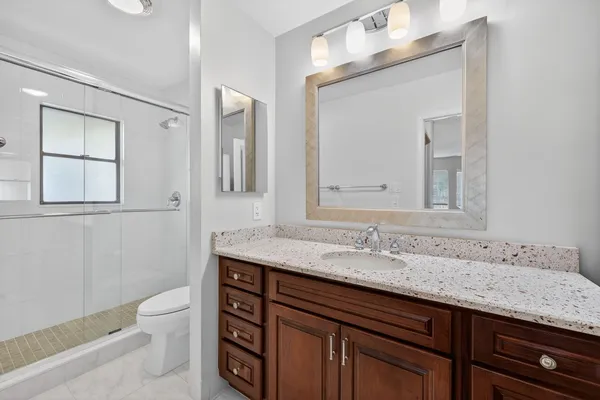 a bathroom with a granite countertop sink a toilet and mirror