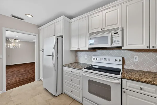 a kitchen with stainless steel appliances granite countertop a refrigerator stove and white cabinets