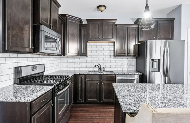 a kitchen with stainless steel appliances granite countertop wooden floor and window