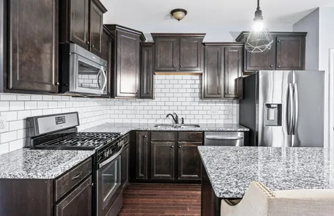 a kitchen with stainless steel appliances granite countertop wooden floor and window