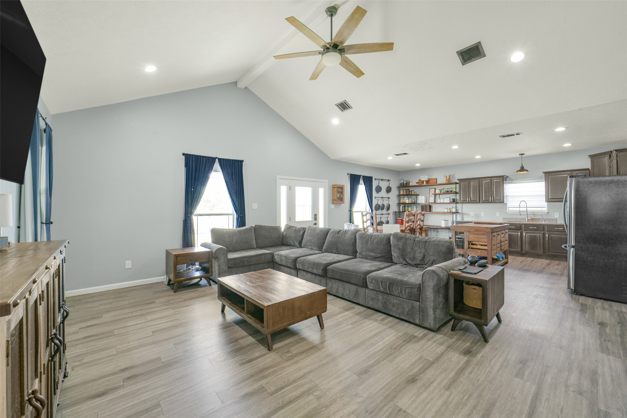 11301 South FM 441 Road El Campo, TX 77437 - Photo 10 of 43 This spacious, open-concept living area features high ceilings with a ceiling fan, light wood flooring, and abundant natural light from large windows. Modern kitchen with stainless steel appliances, and ample cabinet space, offering a perfect blend of comfort and functionality.