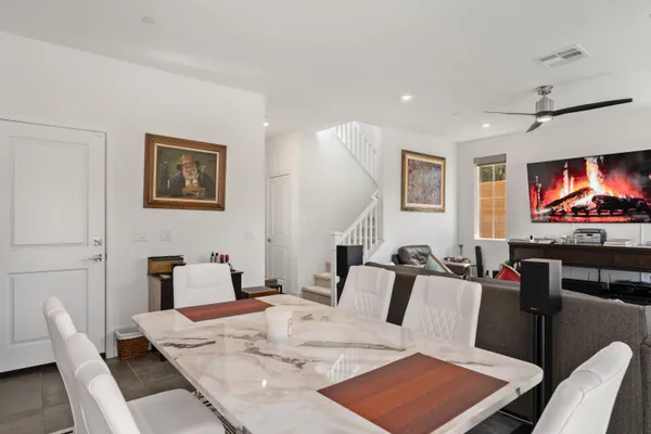 a kitchen with stainless steel appliances granite countertop a sink dishwasher a refrigerator and white cabinets with wooden floor
