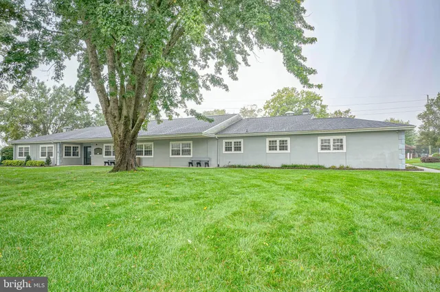 a view of a house with a big yard and large trees