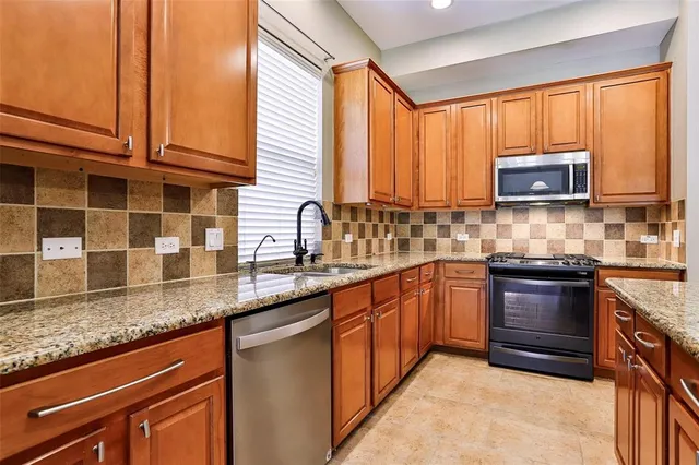 a kitchen with stainless steel appliances granite countertop a sink a stove counter space and cabinets