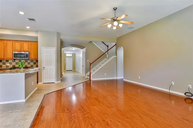 a view of an empty room with wooden floor and a kitchen