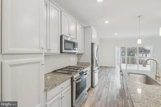 a kitchen with stainless steel appliances granite countertop a refrigerator oven a sink dishwasher and wooden cabinets with wooden floor